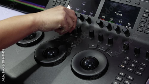 Color grading. Professional colorist operating video color grading control panel. with trackballs knobs and display controls for adjusting color gamma and visual tones in video post production.