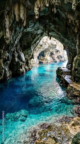 Turquoise water inside a sea cave with stalactites, wooden stairs leading into a limestone grotto.