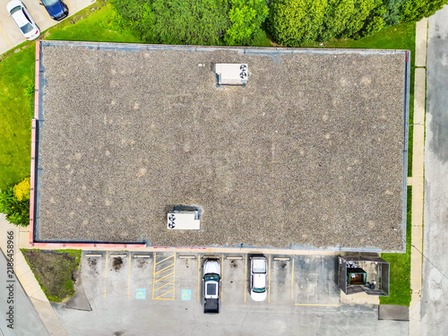Top down aerial view of a flat commercial roof and parking lot with parking spaces drone photography industrial building gravel roof urban development roof texture real estate business park