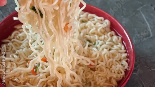 Eating instant ramen with chopsticks in a kitchen setting during a casual meal time