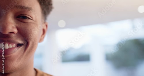 Adult African descent male smiling and widening grin from offscreen prompt by home window