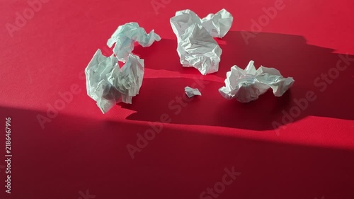 Crumpled paper shapes on a red background showing different angles and shadows during daytime