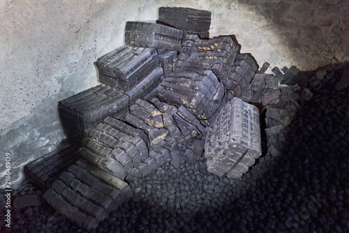 Canvas Print Old coal briquettes and loose fuel stored inside a dark concrete room