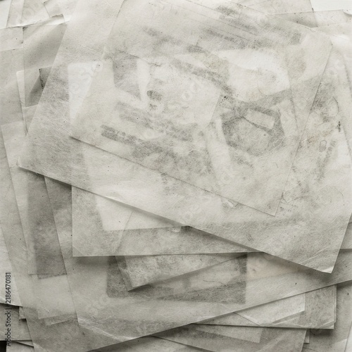 Stack of translucent textured paper sheets with faint abstract charcoal marks layered on top of each other