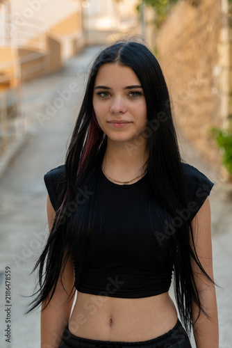 Young woman with long black hair standing in narrow alleyway