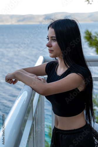 Young woman leaning on railing and gazing thoughtfully over the
