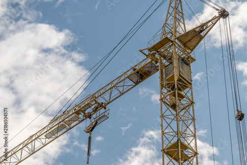 Construction crane standing tall against a bright blue sky with fluffy white clouds showcasing industrial progress and urban development