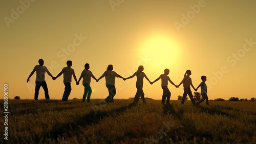 Large group people strolling on grass in sun. Parents children, holding hands, play in park. Happy family outing. Dad mom children playing outdoors. People holding hands, Dream Family, silhouette.