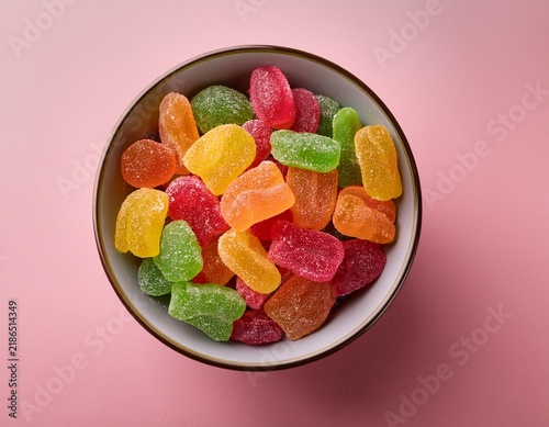 bright bowl of assorted colorful gummy candies on pink background