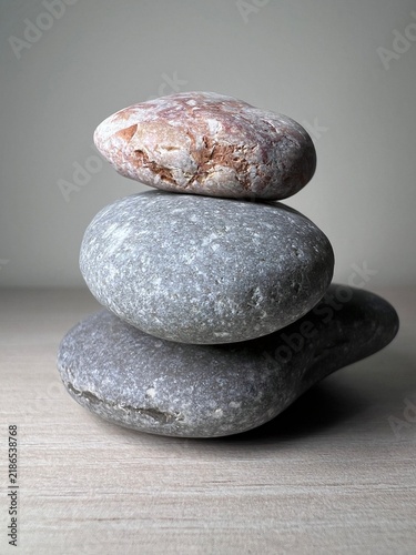Fotografie Stacked Stones Balancing Against Plain Wall