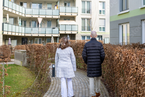 Quadro su tela Middle aged couple walking in modern residential area, calm suburban lifestyle,