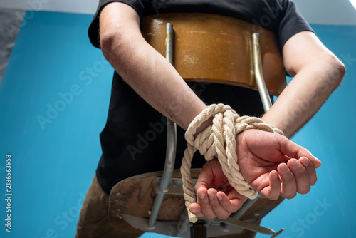 Foto A man's hands are tied with a rope and he is sitting on a chair.