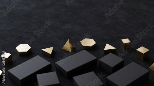 Geometric Shapes Arranged on a Dark Textured Surface with Brass and Black Objects