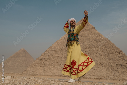 Foto Smiling Arab male folk dancer in vibrant yellow embroidered robe and turban caug