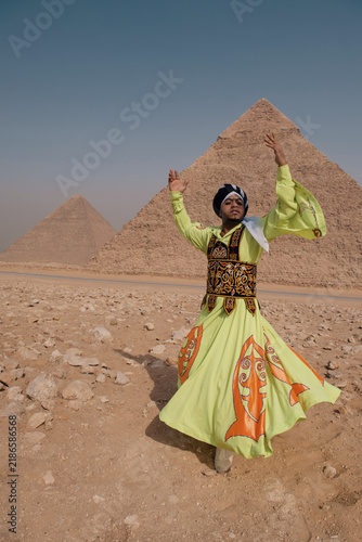 Obraz na plátně Tanoura dancer in vivid lime green and orange embroidered robe raises both arms