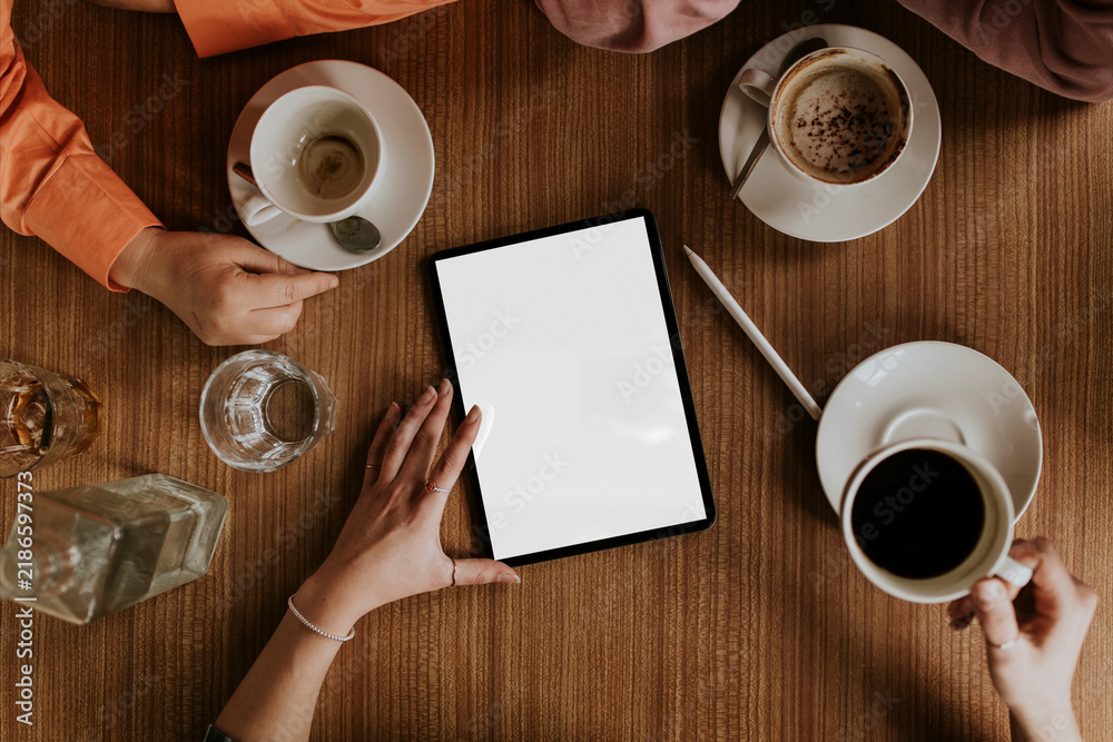 Obraz premium Overhead view of friends enjoying coffee around tablet