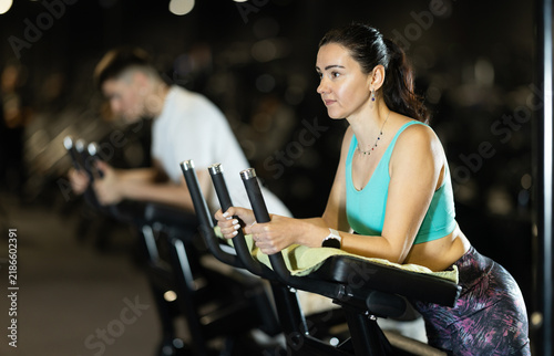 Bild auf Leinwand In gym, woman uses gym apparatus to strengthen leg muscles