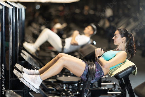 Fotografía In gym, woman uses gym apparatus to pump up press