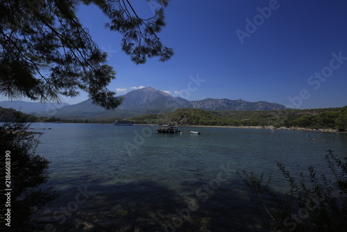 Tranquil coastal landscape of Phaselis cove surrounded by pine trees, blue Mediterranean sea, and mountain range in Antalya
