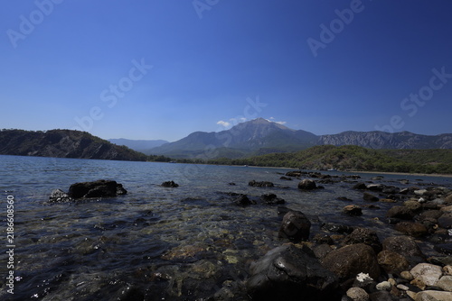 Tranquil coastal landscape of Phaselis cove surrounded by pine trees, blue Mediterranean sea, and mountain range in Antalya