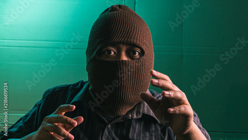 Картината върху платно Intimidating Indonesian adult male wearing brown balaclava mask displaying grabb