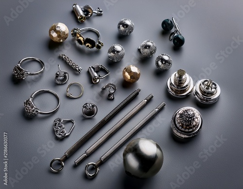 jewelry composition featuring various body piercing accessories on a gray background