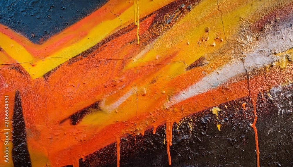 Naklejka premium a close up view of a wall reveals graffiti in vibrant orange and yellow colors showcasing texture detail and paint splatter in a street art style