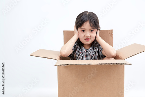 Fotografía A mischievous and adorable Asian little girl playing in a cardboard box