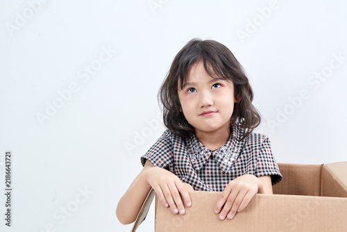 Fotografía A mischievous and adorable Asian little girl playing in a cardboard box