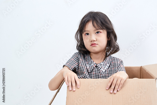 Obraz na płótnie A mischievous and adorable Asian little girl playing in a cardboard box