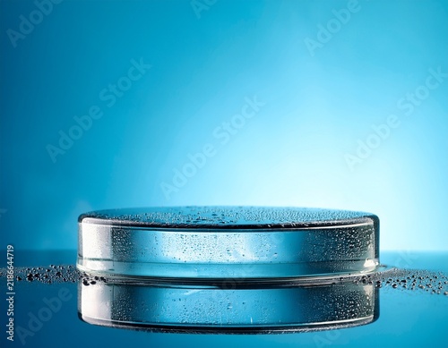 glass cosmetic podium with water drops on light blue background for product mockup display