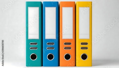  Four upright ring binders teal blue orange yellow side by side flat surface rectangular label holders metal rings circular reinforced holes plain light gray background office organization supplies