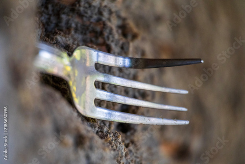 Foto Conceptual macro shot of a metallic fork set against a textured earthen and ston