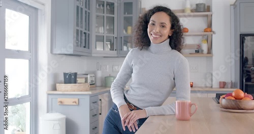 African American woman leaning on kitchen island, pink mug, smiling at camera during slow zoom
