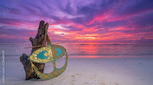 Traditional Malaysian Wau Bulan kite on tropical beach at vibrant sunset