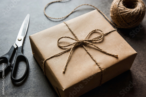 Brown paper package tied with twine beside scissors and a twine ball, minimalist craft