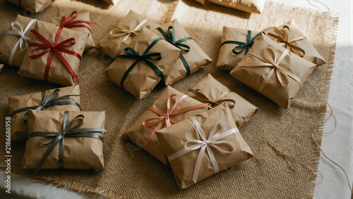 Small kraft packages with colorful ribbon bows arranged on burlap fabric