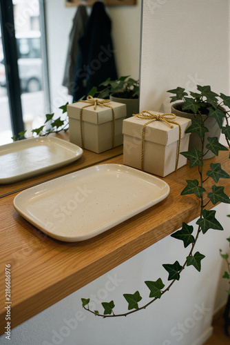 Beige gift boxes with gold twine on a wooden shelf with trailing ivy and a mirror