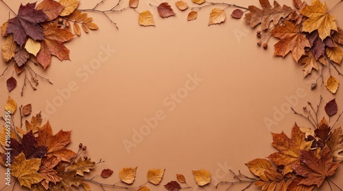 Autumn border frame composed of dried maple and oak leaves with small twigs on a warm light brown background, with copy space