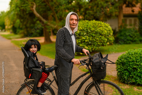 Father and child in Halloween costumes ride a bicycle together