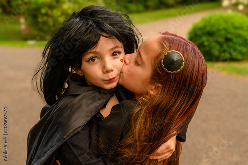 Young girl in black cloak hugs another child