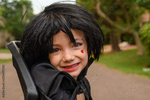Child smiles with black hair and red cheek mark