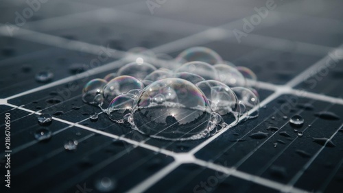 Solar panel surface with iridescent soap bubbles and water droplets represents renewable energy maintenance and panel cleaning.