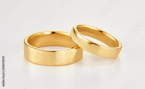 Pair of polished gold wedding bands rings isolated on white background close up