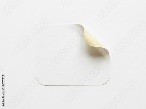 Blank square paper sticker with a curled corner isolated on a white background