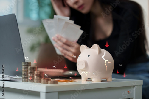 Financial crisis concept with cracked piggy bank coins and stressed woman for inflation loss