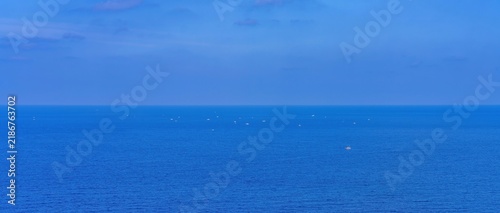 釣り船が集まる青い海と水平線のパノラマ背景 コピースペースと遠くの船