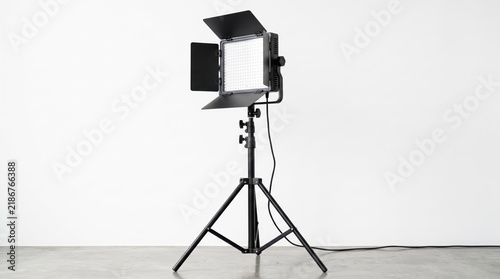 Professional LED video light panel on tripod stand with barn doors isolated on white background, studio lighting equipment for photography, filmmaking and content creation.