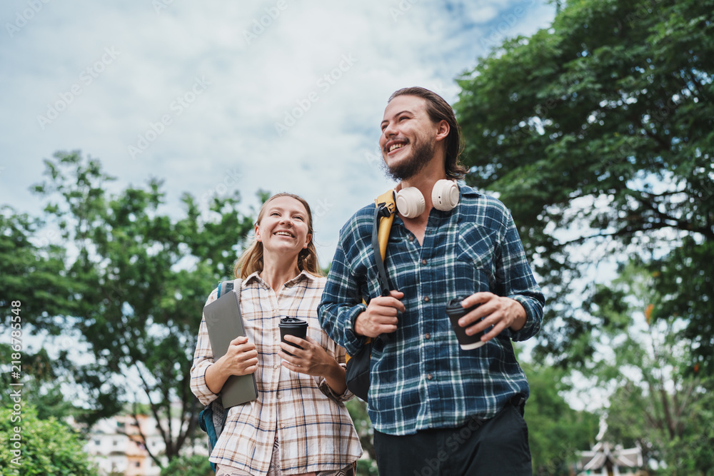 Obraz premium Happy students walking outdoors on campus with coffee