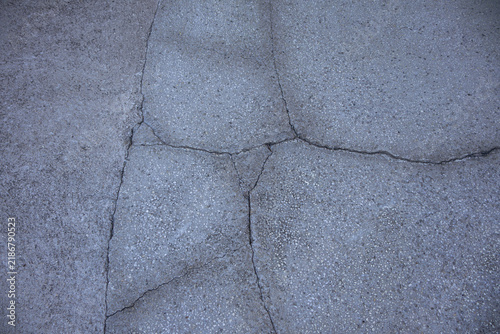 Cracked gray pavement with exposed aggregate forming an irregular textured background